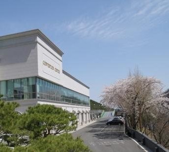 “CONVENTION CENTER” 간판이 있는 컨벤션 건물과 길가의 벚꽃, 맑은 봄 하늘